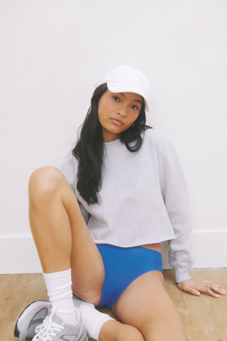 young woman with baseball cap sitting in period underwear